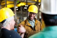 Multi-ethnic workers wearing hard hats, talking